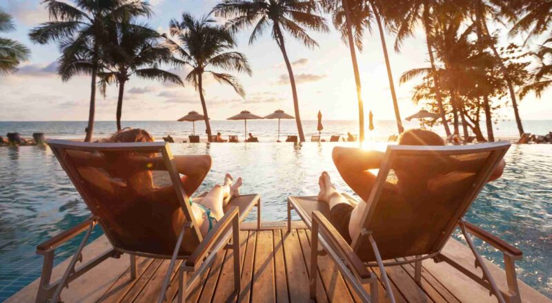 Two individuals sitting on beach chairs near pool