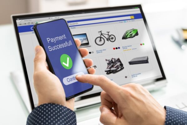 Hand holding mobile phone with screen indicating successful purchase