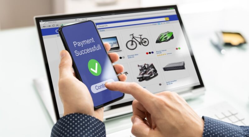 Hand holding mobile phone with screen indicating successful purchase