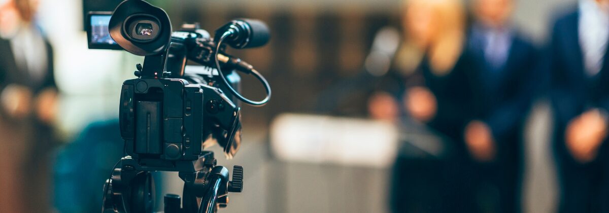 Close up of TV camera filming speakers.