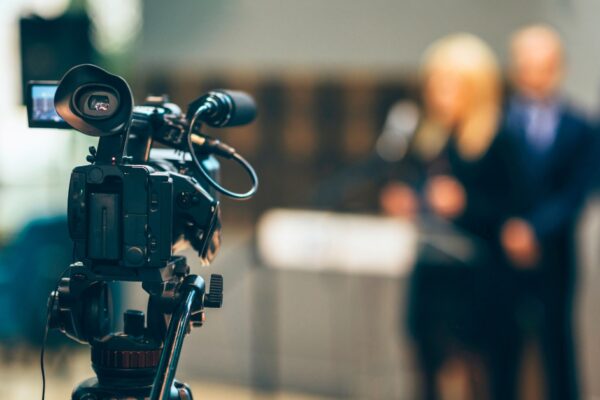 Close up of TV camera filming speakers.