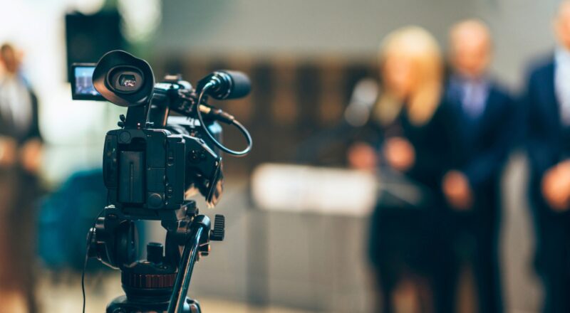 Close up of TV camera filming speakers.
