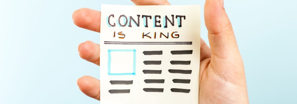 Hand holding a sticky note saying Content is King