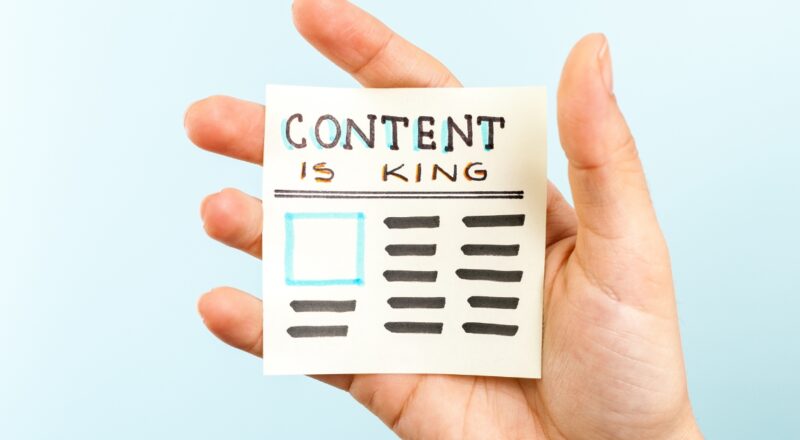 Hand holding a sticky note saying Content is King