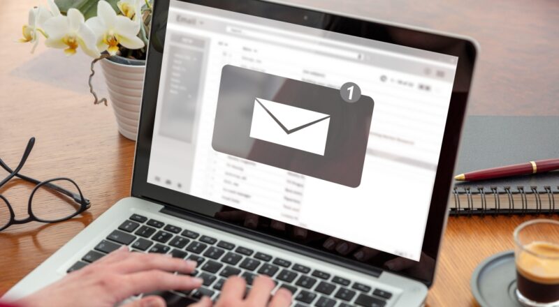 Person typing on the computer with an unread email icon on the screen